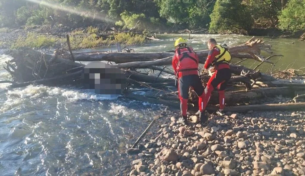 A vítima, que estava parcialmente submersa e presa em galhos, foi retirada do rio pelos socorristas.