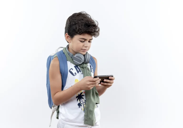 little schoolboy wearing back bag and headphones playing on phone isolated on white background with copy space | Foto: stockking