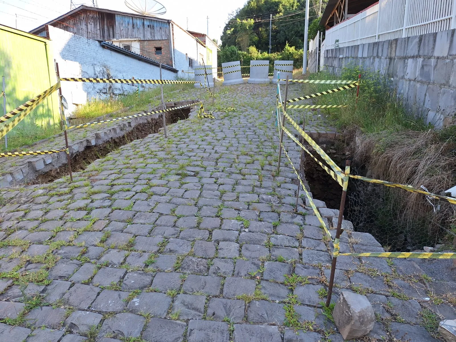 Após as enchentes de maio, a via sofreu deslizamentos de paralelepípedos e o surgimento de buracos, comprometendo a estrutura da galeria de drenagem