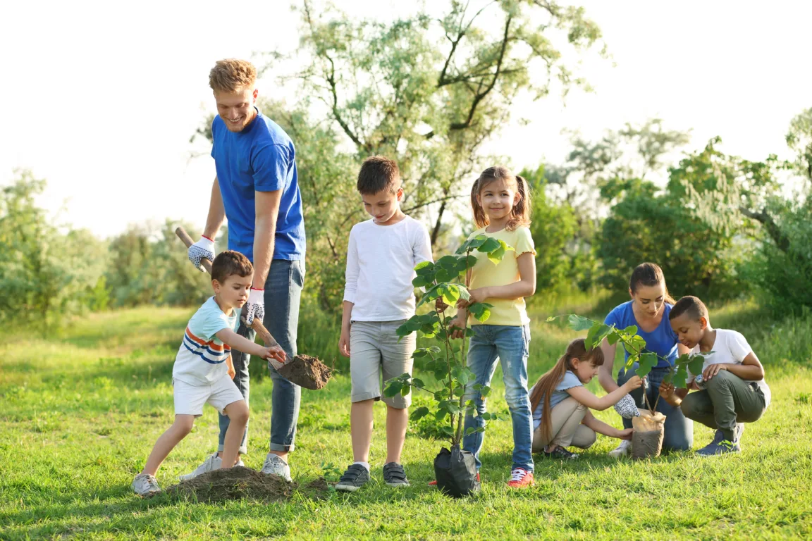Kids planting trees with volunteers in park