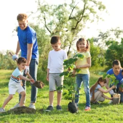 Kids planting trees with volunteers in park