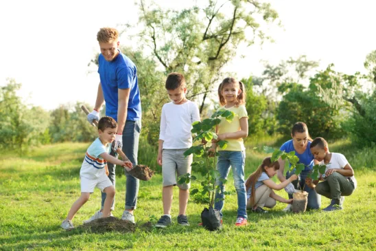 Kids planting trees with volunteers in park