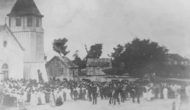 Foto antiga em preto e branco de um evento com pessoas em frente a uma igreja e edifícios.