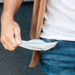 Homem mostrando o bolso vazio, simbolizando falta de dinheiro ou dificuldades financeiras.