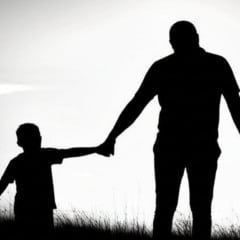 Silhuetas de pai e filho de mãos dadas em um cenário ensolarado, simbolizando união.