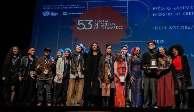 Grupo de pessoas no palco do Festival de Cinema de Gramado, incluindo premiados.
