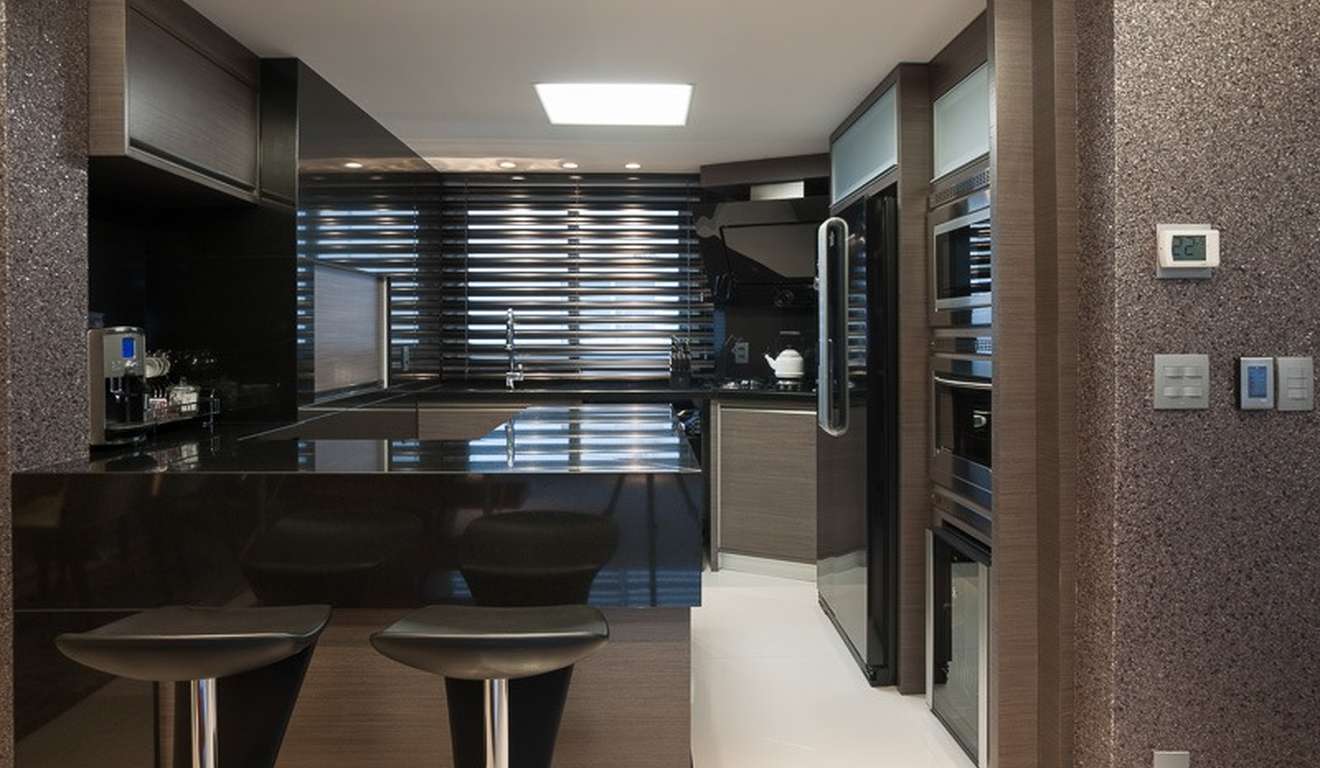 Interior de cozinha moderna com bancada preta, banquetas e eletrodomésticos.