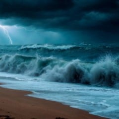 Tempestade no mar com raios, ondas quebrando na praia e céu escuro.