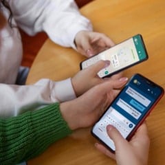 Duas pessoas usando seus smartphones para conversar por mensagens, com foco em detalhes da tela e teclado.