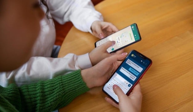 Duas pessoas usando seus smartphones para conversar por mensagens, com foco em detalhes da tela e teclado.