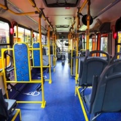 Interior de ônibus urbano, com assentos e barras amarelas, corredor azul e janelas laterais. Interior de ônibus urbano, com assentos e barras amarelas, corredor azul e janelas laterais.