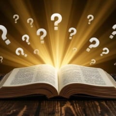 Livro aberto com raios de luz e pontos de interrogação flutuando, simbolizando perguntas e conhecimento.