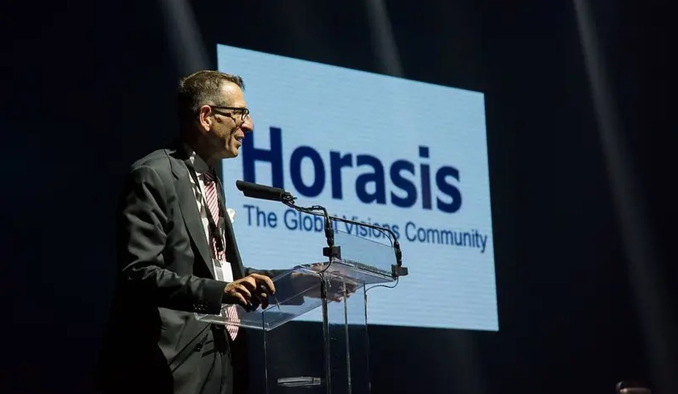 Palestrante em evento Horasis. Logotipo Horasis e slogan 'The Global Visions Community' no fundo. Palestrante em evento Horasis. Logotipo Horasis e slogan 'The Global Visions Community' no fundo.