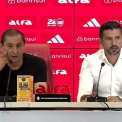Dois homens em uma coletiva de imprensa com logotipos de patrocinadores ao fundo.