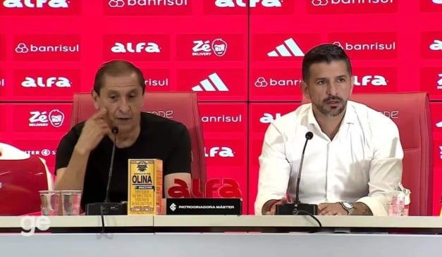 Dois homens em uma coletiva de imprensa com logotipos de patrocinadores ao fundo.