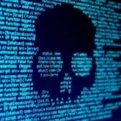 Imagem mostrando código de computador em tom azul com uma silhueta de caveira, simbolizando cibersegurança e hacking.
