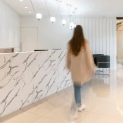 Interior de escritório moderno com balcão de mármore e pessoa em movimento.