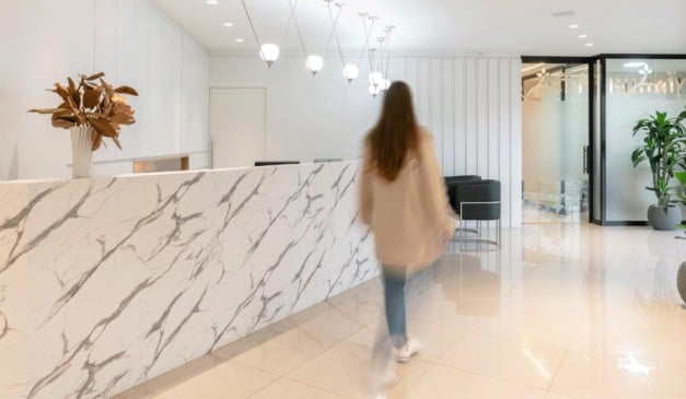 Interior de escritório moderno com balcão de mármore e pessoa em movimento.
