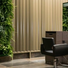 Interior de sal&atilde;o de beleza com parede de plantas, espelhos e cadeiras.