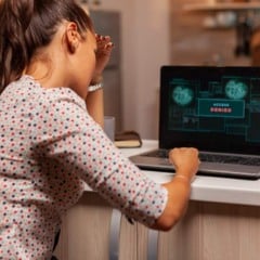 Mulher frustrada com acesso negado no laptop, tela exibe 'acesso negado'.