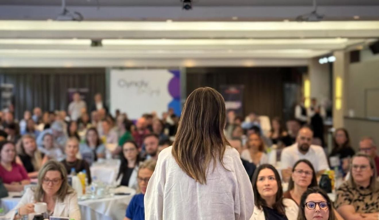 Palestrante fala para plateia em evento corporativo, vista por trás, com foco na audiência. Palestrante fala para plateia em evento corporativo, vista por trás, com foco na audiência.