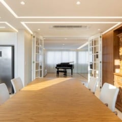 Sala de jantar elegante com mesa de madeira, cadeiras e piano ao fundo.