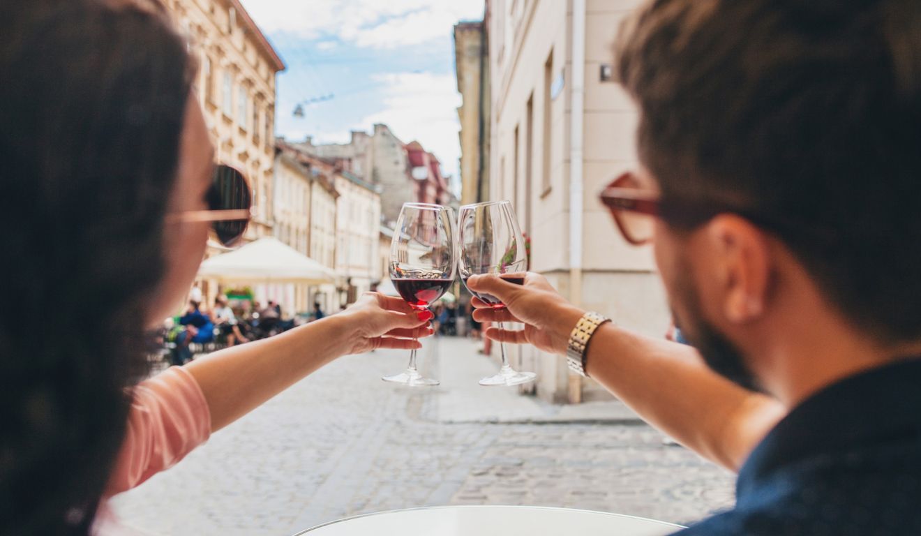 Casal brindando com vinho em um restaurante ao ar livre, com edifícios históricos ao fundo. Casal brindando com vinho em um restaurante ao ar livre, com edifícios históricos ao fundo.