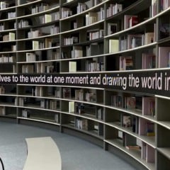 Estante de livros curva com ilumina&ccedil;&atilde;o e frase inspiradora.