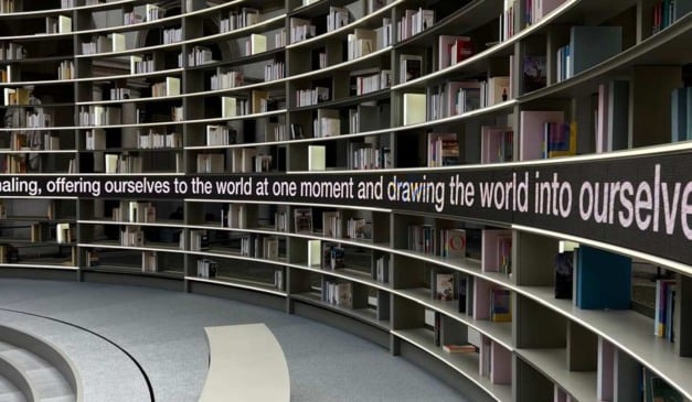 Estante de livros curva com iluminação e frase inspiradora.