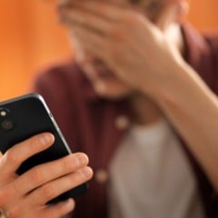 Homem chocado olhando para o celular, cobrindo o rosto com a m&atilde;o.