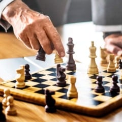 M&atilde;o de um jogador movendo pe&ccedil;a de xadrez sobre tabuleiro.