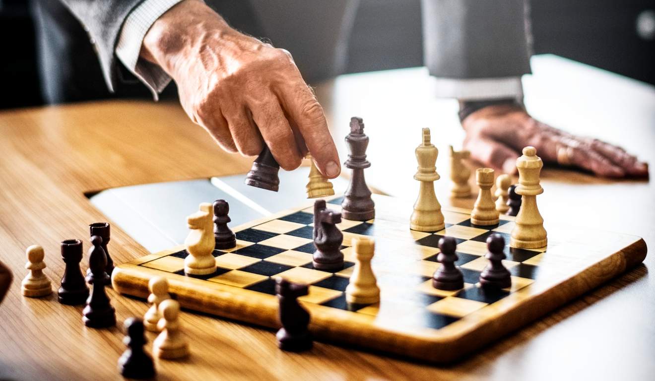 Mão de um jogador movendo peça de xadrez sobre tabuleiro.